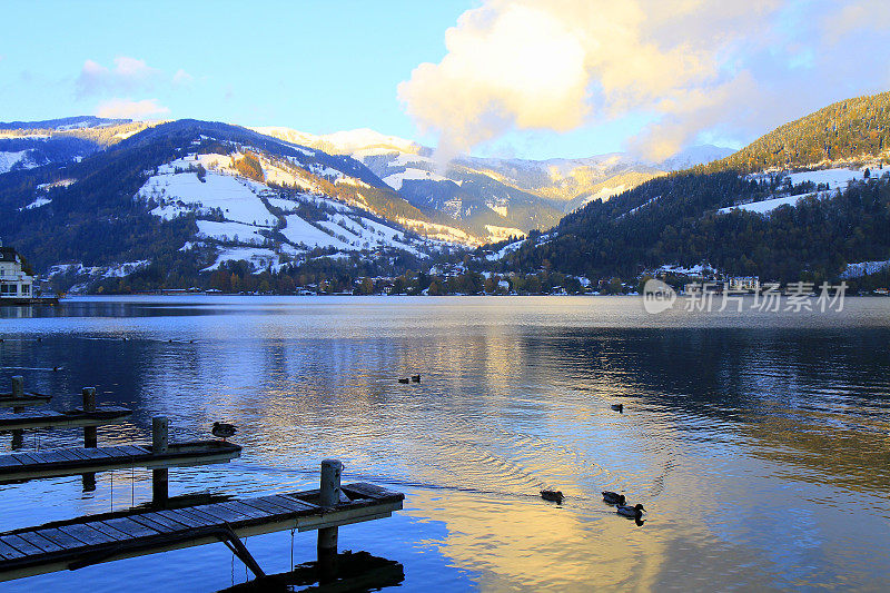 木制的码头和一群鸭子漂浮在美丽的泽勒湖上，泽尔am See，萨尔茨堡，奥地利